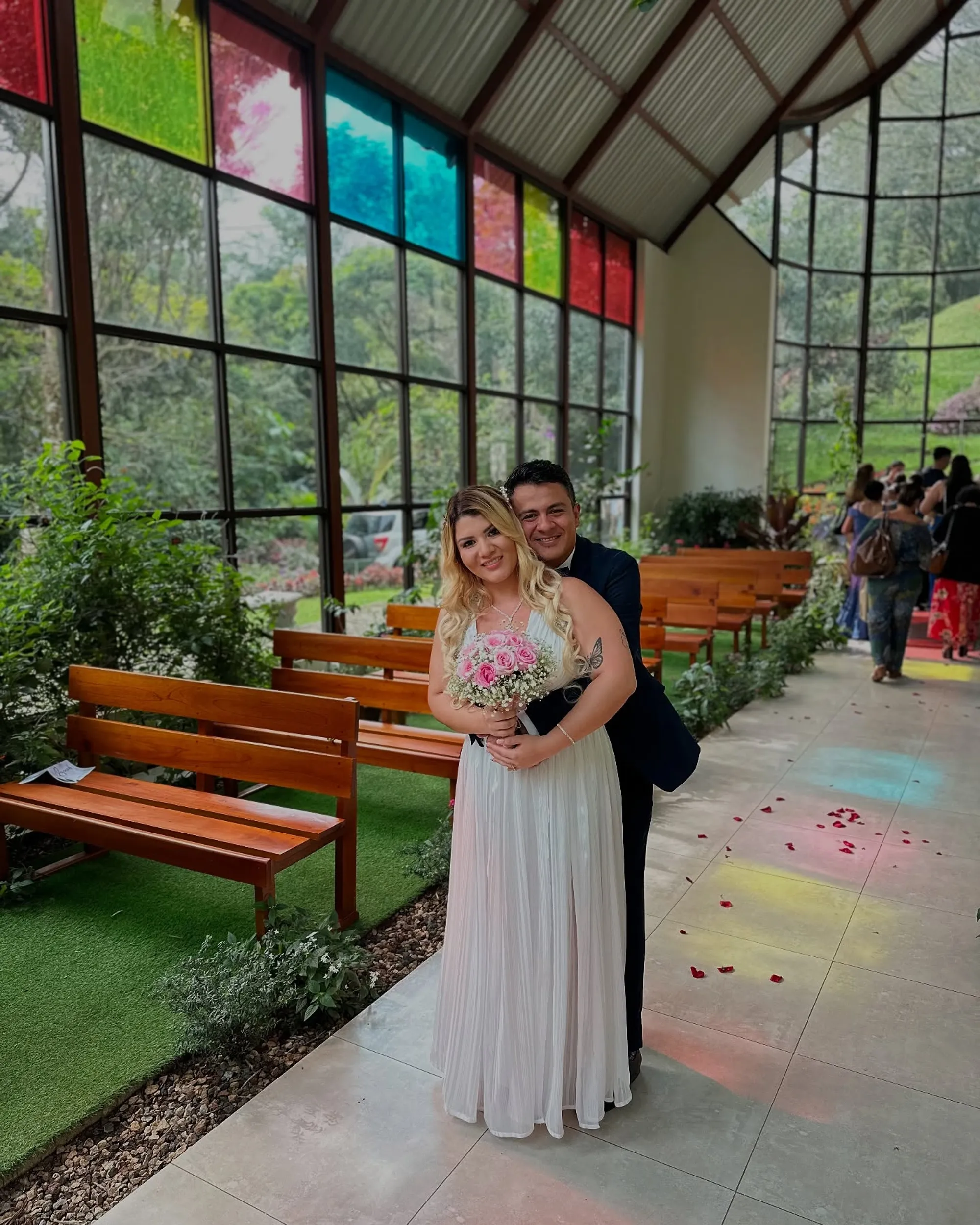 Ceremonia celebrándose en la capilla, con las bancas de madera ocupadas y el jardín alrededor.
